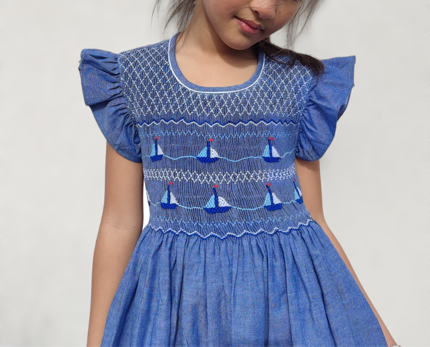 Robe à smocks bleu chambray motif bateaux avec petites manches volantes. Robe fille estivale.