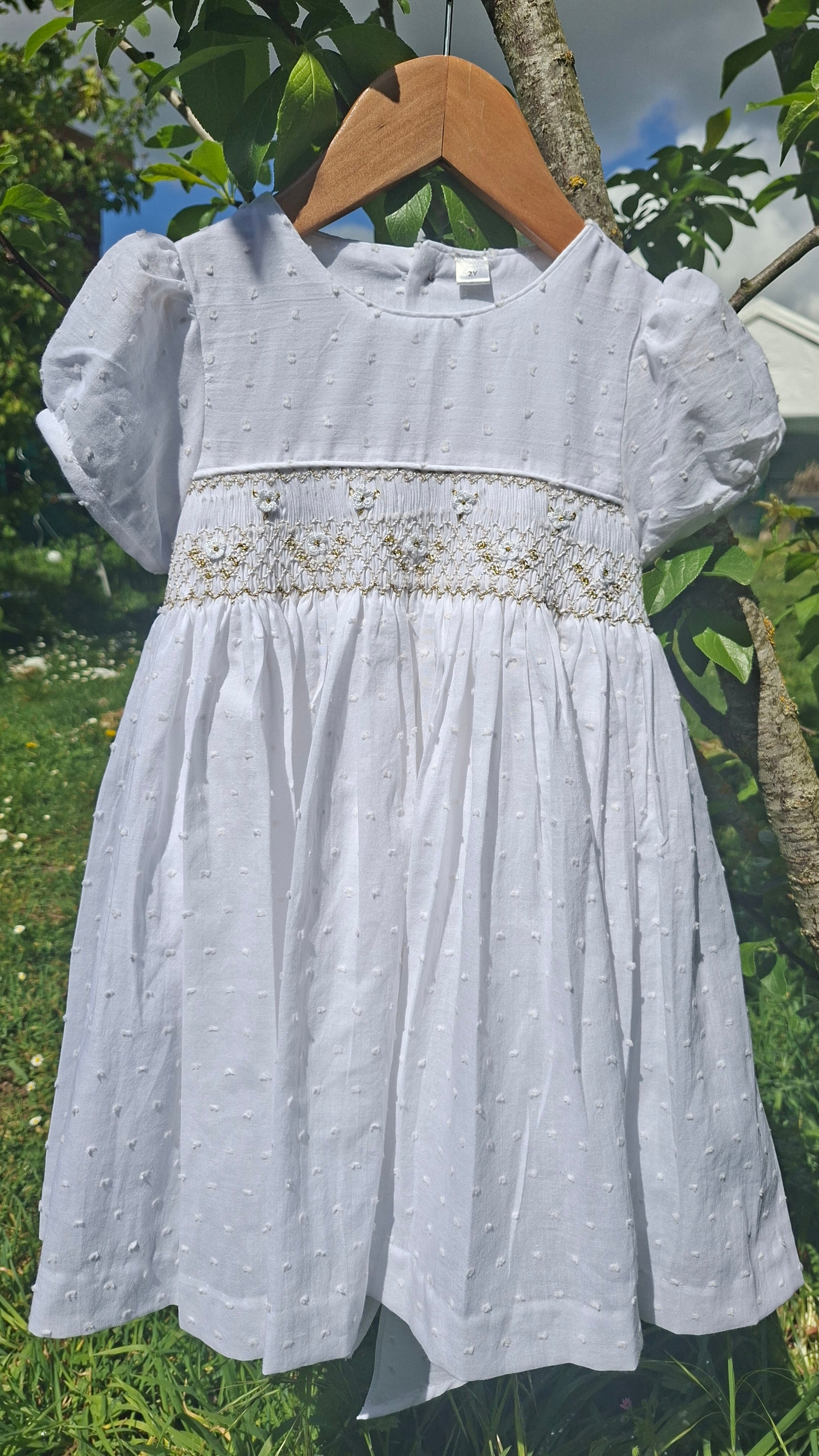 Robe à smocks en plumetis blanc et broderie dorée