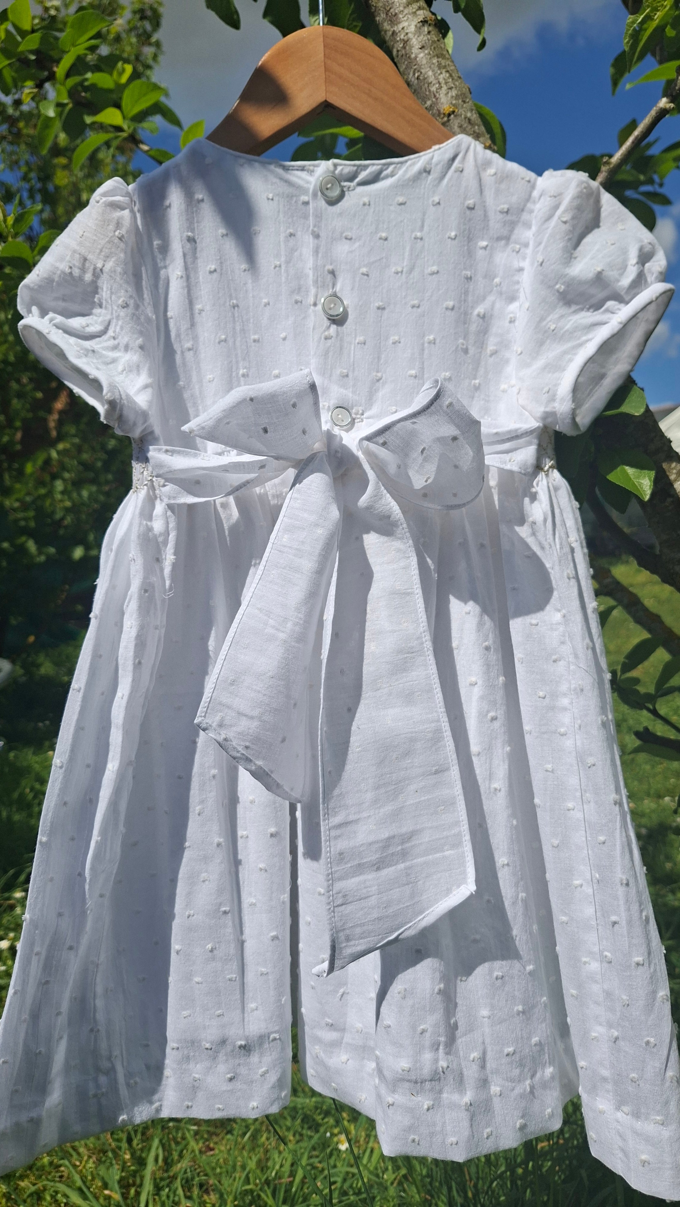 Robe à smocks en plumetis blanc et broderie dorée
