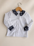 Chemise garçon blanche à col et poignets à carreaux marine.