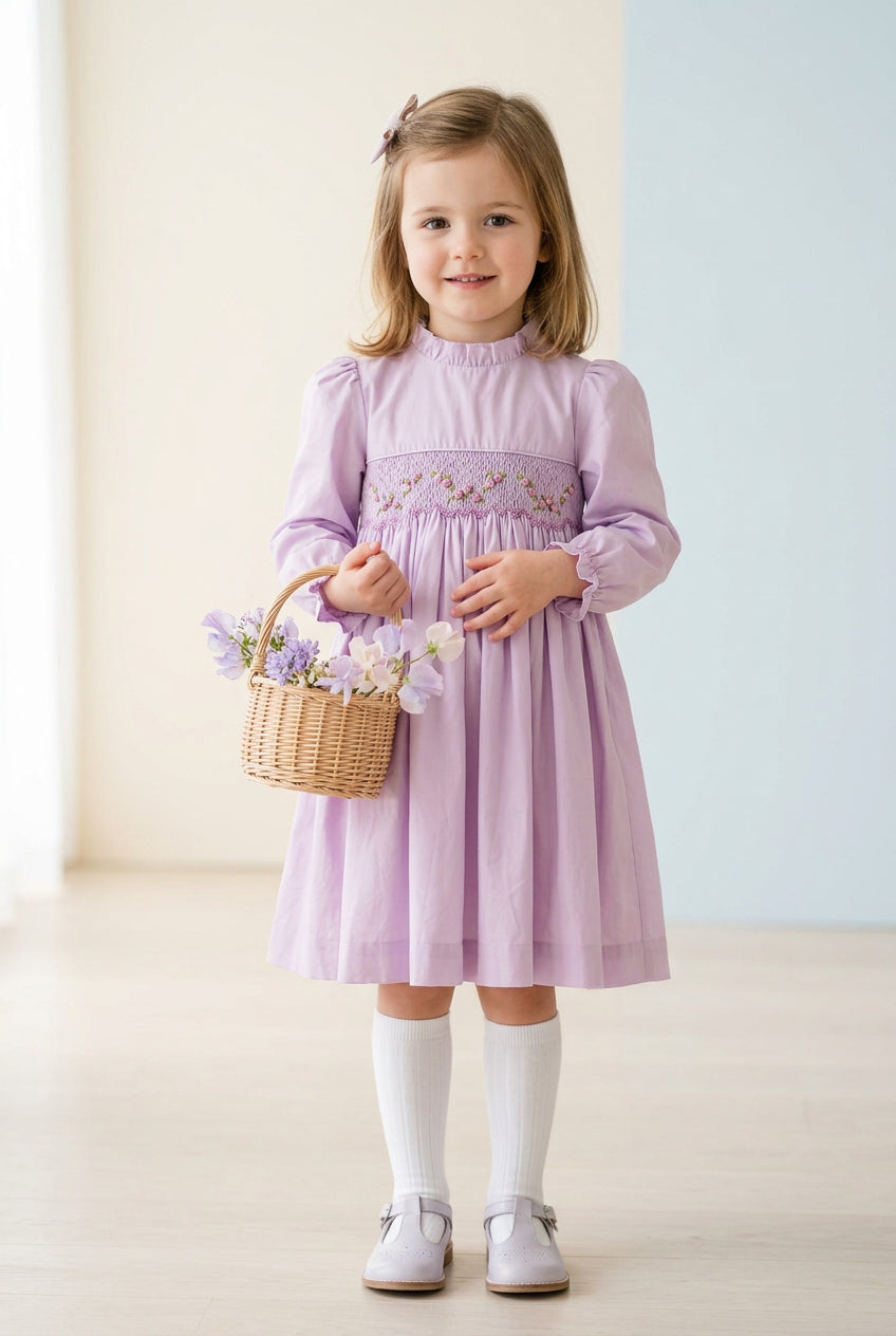 Vue de face de la robe fille parme lilas, avec smocks fleuris, col volanté et manches longues.